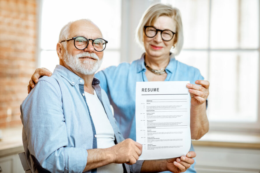 Portrait of a happy senior couple holding resume document indoors. Concept of work in older age